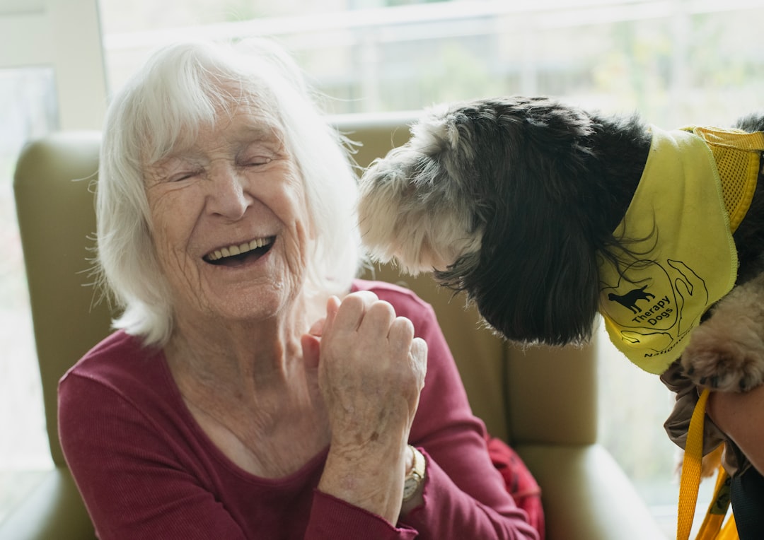 nursing home therapy dog — Elderly woman laughing with a dog