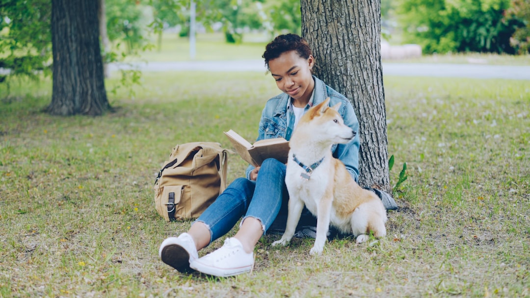 hospital therapy dog — A person reads a book with their dog outdoors.