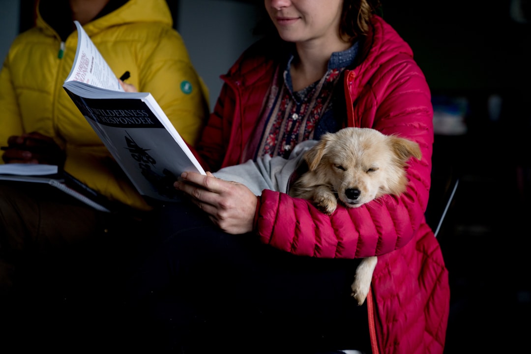 school reading programs — A woman is holding a dog and reading a book