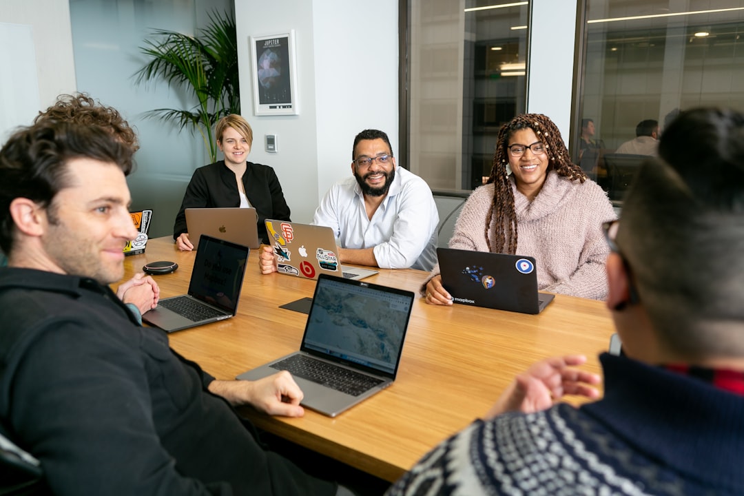 therapy dog organizations — four people all on laptops, two men and two women, listen to person talking in a board meeting 